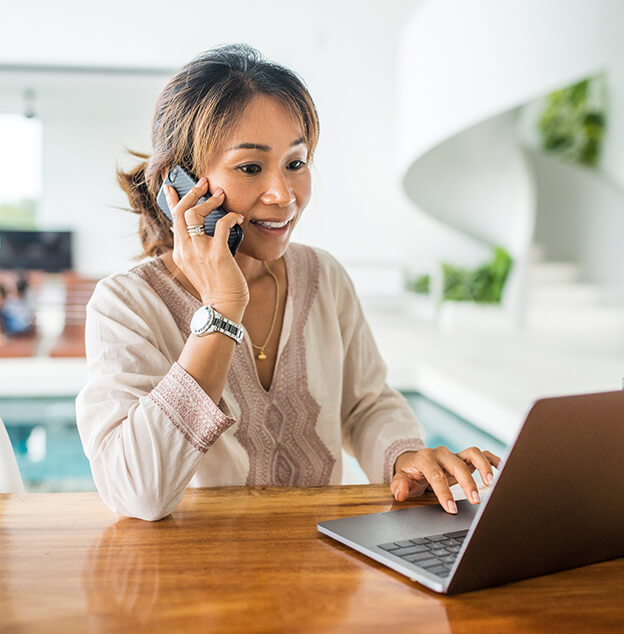 woman talking on her phone and looking at her laptop