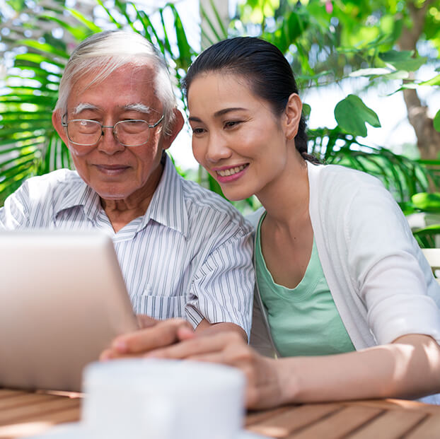 woman helping her senior father with an online search on a tablet device