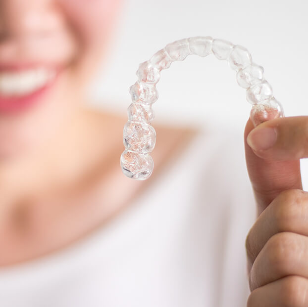 closeup of a person holding their clear aligners
