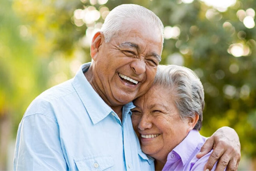 senior couple hug and smile after learning about the benefits of dentures