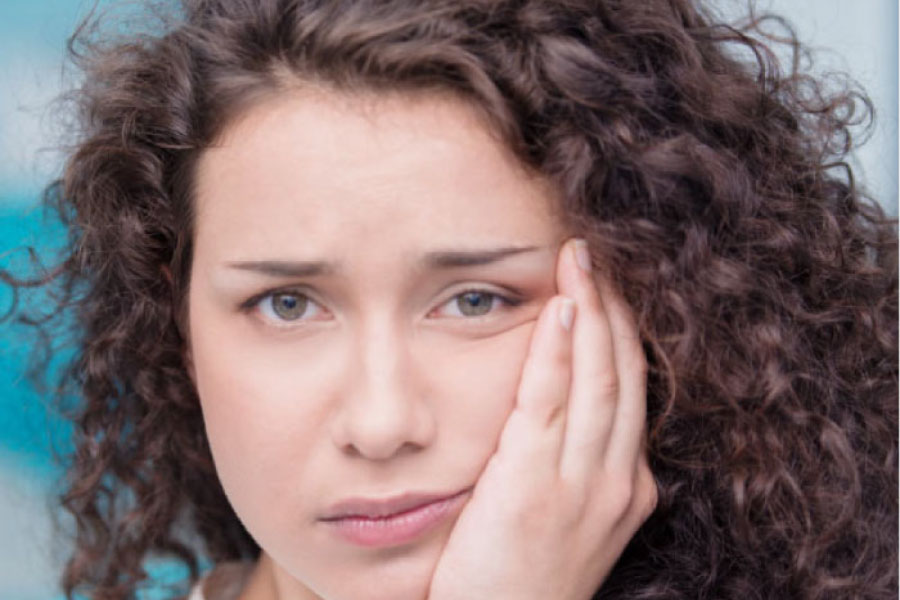 young woman holding her jaw in pain after wisdom teeth removal