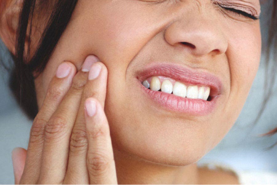 woman holds her cheek in pain from a tooth infection