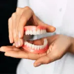 set of dentures being held in two hands