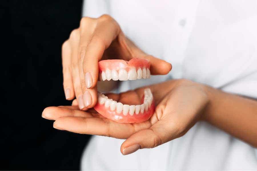 set of dentures being held in two hands