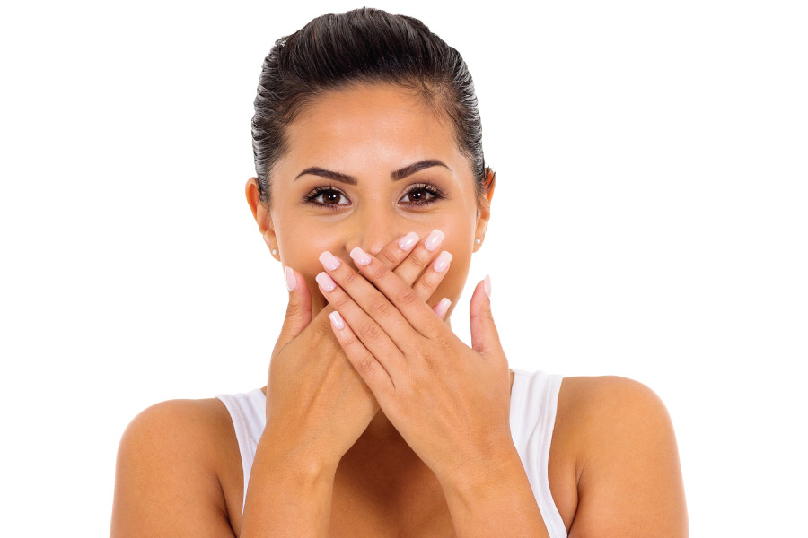 young woman covers her mouth with both hands to hide bad breath