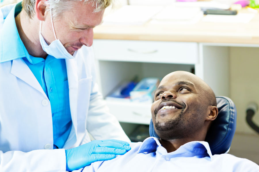 man sitting in the dentist chair discusses the need for dental crowns with the dentist