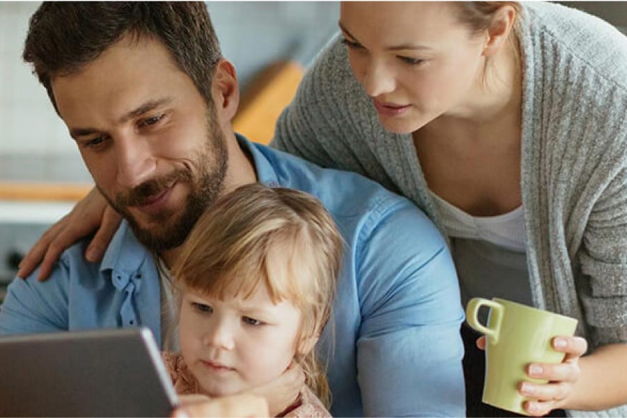 young family of three reviews their dental plan on a laptop computer