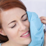 woman holds an ice pack to her jaw to help with tooth pain